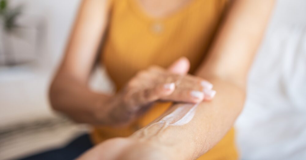 Woman applying cream on her arm