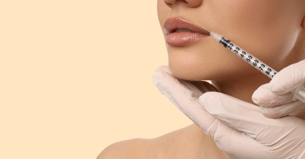 Provider in gloves administering a lip filler injection to a female
