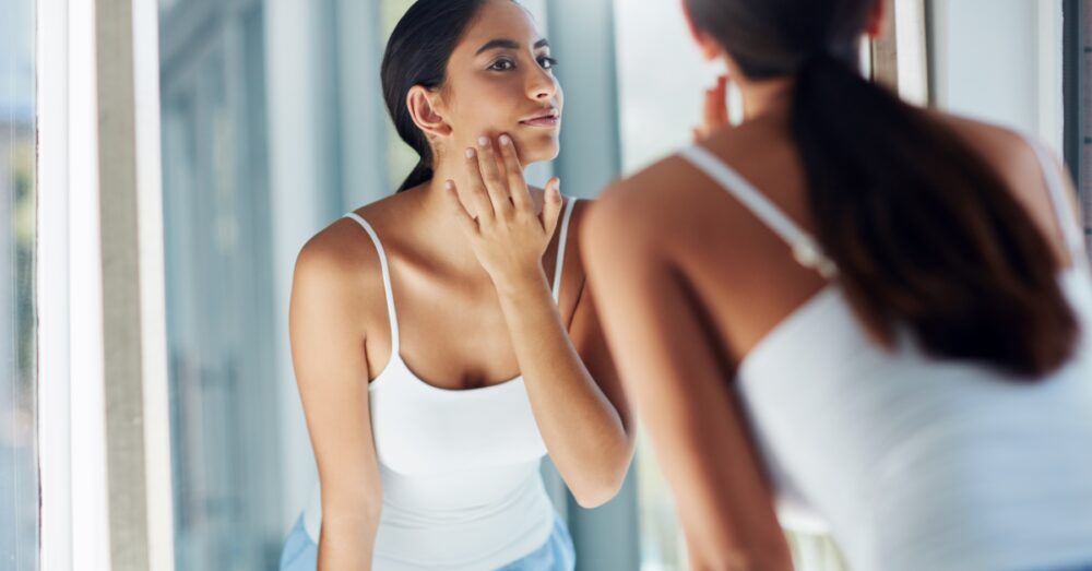 Woman looking at her skin in a mirror after a skin rejuvenation treatment