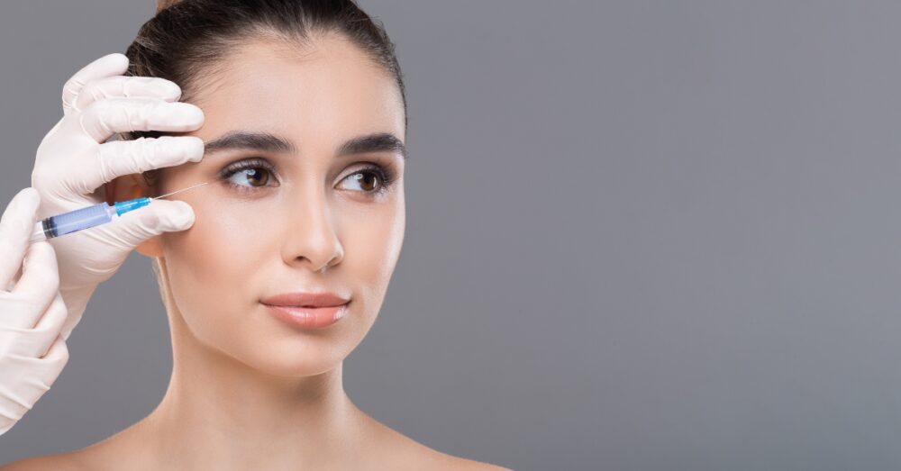 Woman receiving a Botox injection near the brow area from a provider holding a syringe