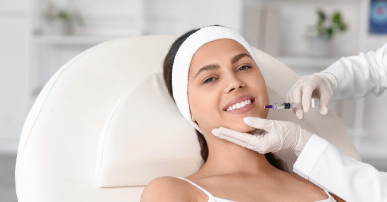 Provider administering lip filler to a smiling woman with a thin needle during. Not a real patient