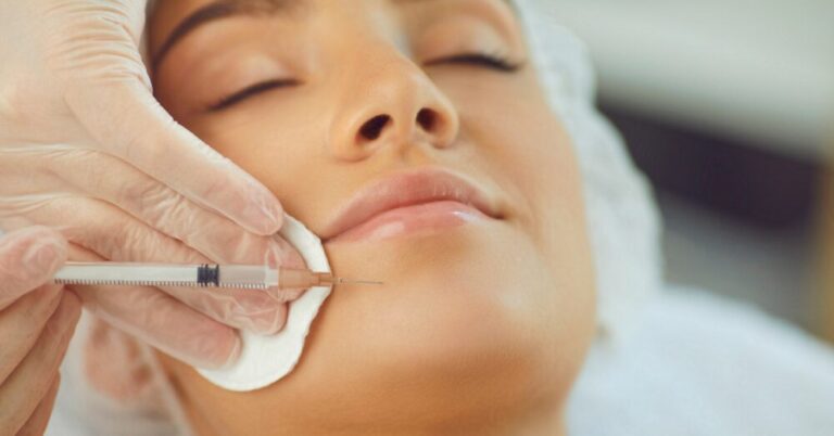 A woman receiving a cosmetic injection near her jawline from a gloved provider during a baby Botox treatment session