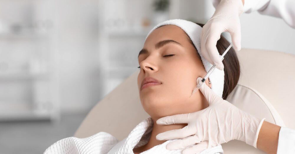 Woman receiving injections near her jawline for facial balancing