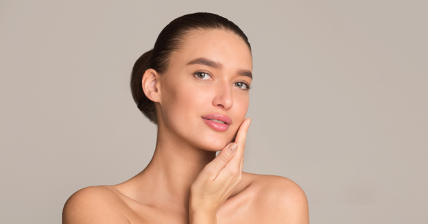 Woman gently touching her face against a neutral background